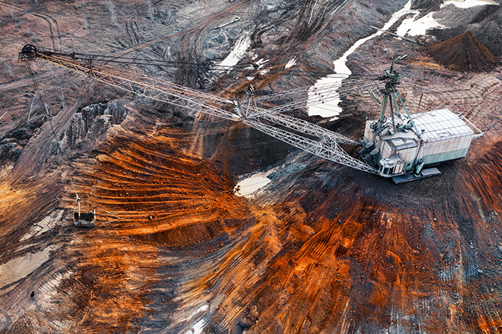 A large walking excavator works in a quarry for the extraction of rare metals. Drone view. Industrial landscape.