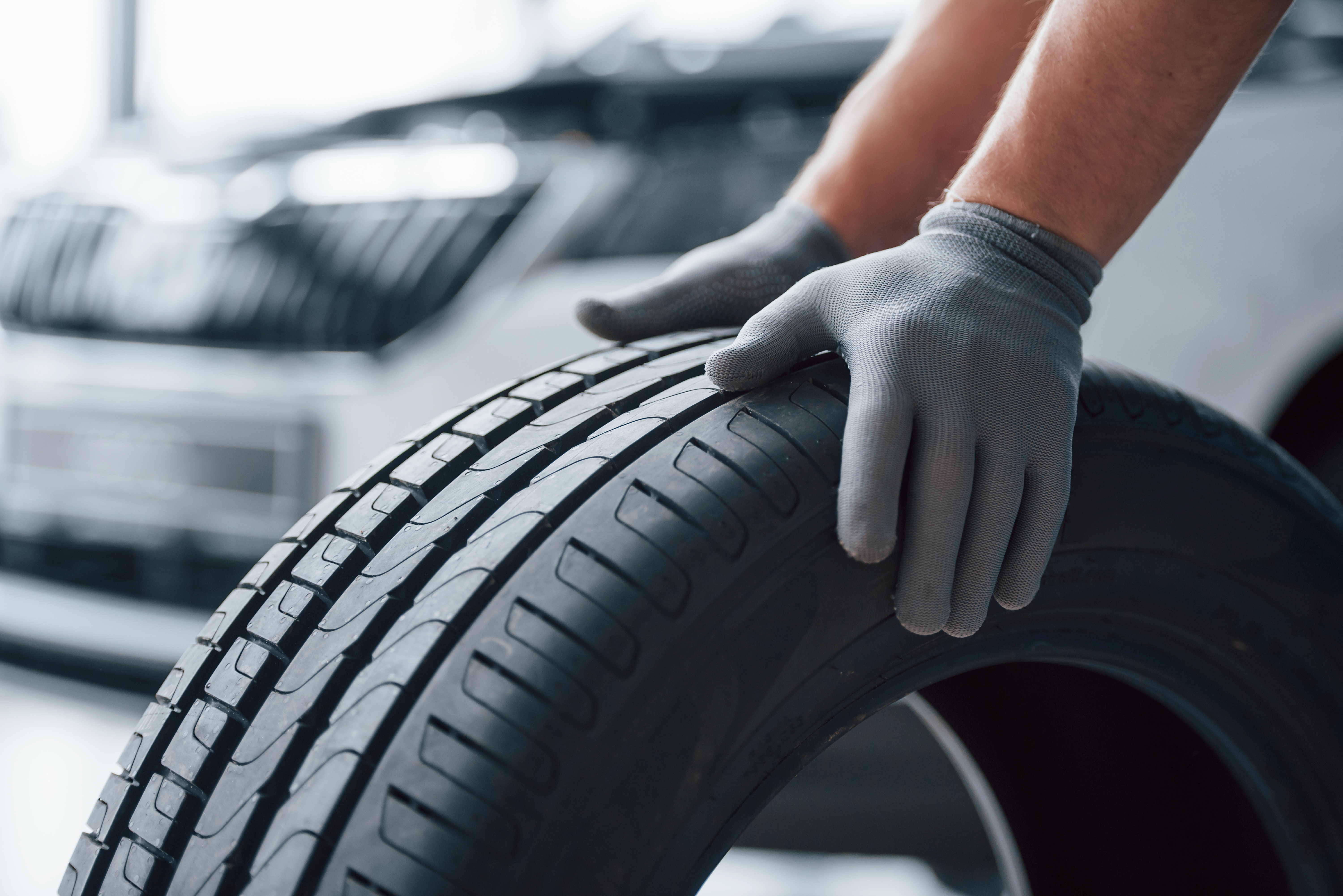 Hands only. Mechanic holding a tire at the repair garage. Replacement of winter and summer tires.